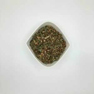 Die weiße rautenförmige Porzellanschale enthält grün-graue mittelgrob geschnittene Blätter und gelb-braune Gewürzstückchen