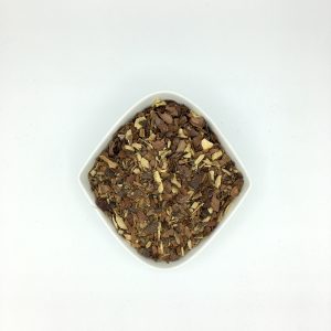 Die weiße rautenförmige Porzellanschale enthält vorwiegend braune Gewürzstückchen mit einigen gelben Wurzelstücken.