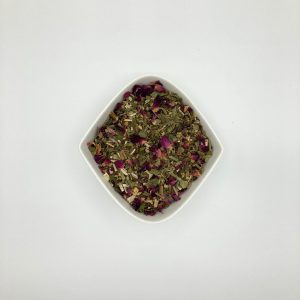 rautenförmige Porzellanschale mit geschnitten Kräutern und Rosenblütenblättern